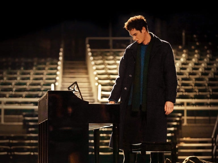 Andrew Garfield as Jonathan Larson, standing at the piano