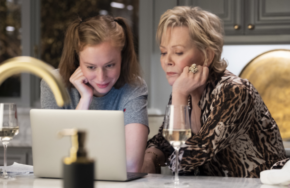 Hannah Einbinder and Jean Smart sit at a table looking at a laptop