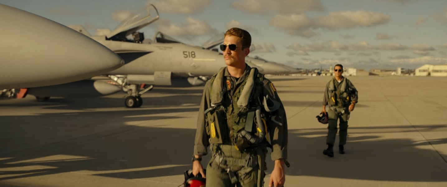 Tom Cruise follows Miles Teller down a runway in Top Gun: Maverick