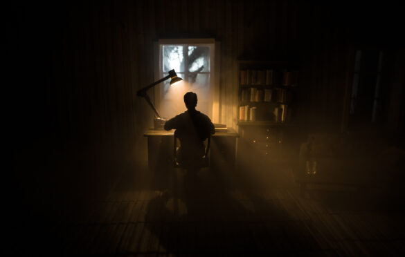 a writer at his desk in a dark room