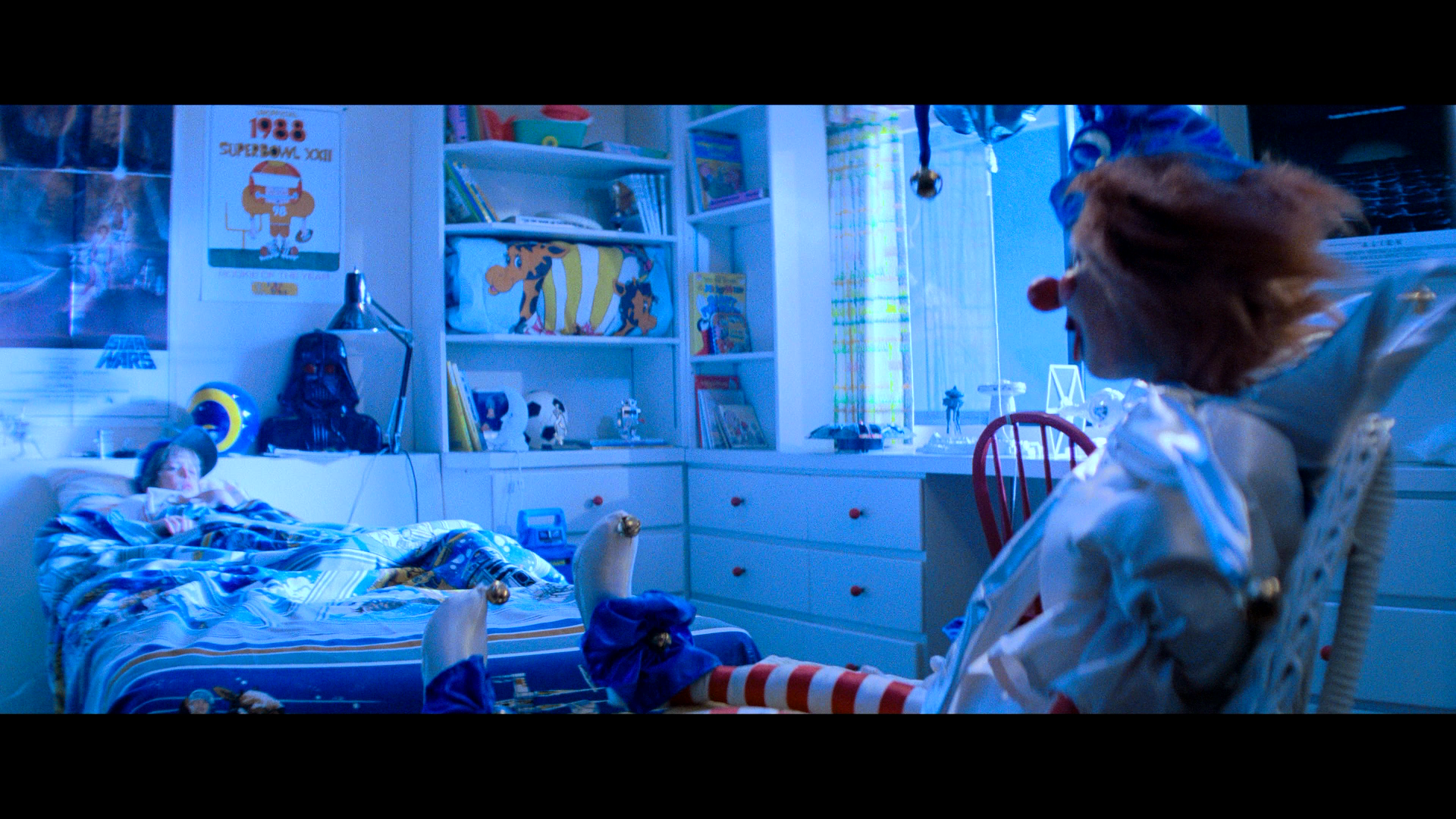 Robbie lies in bed facing a scary clown in Poltergeist