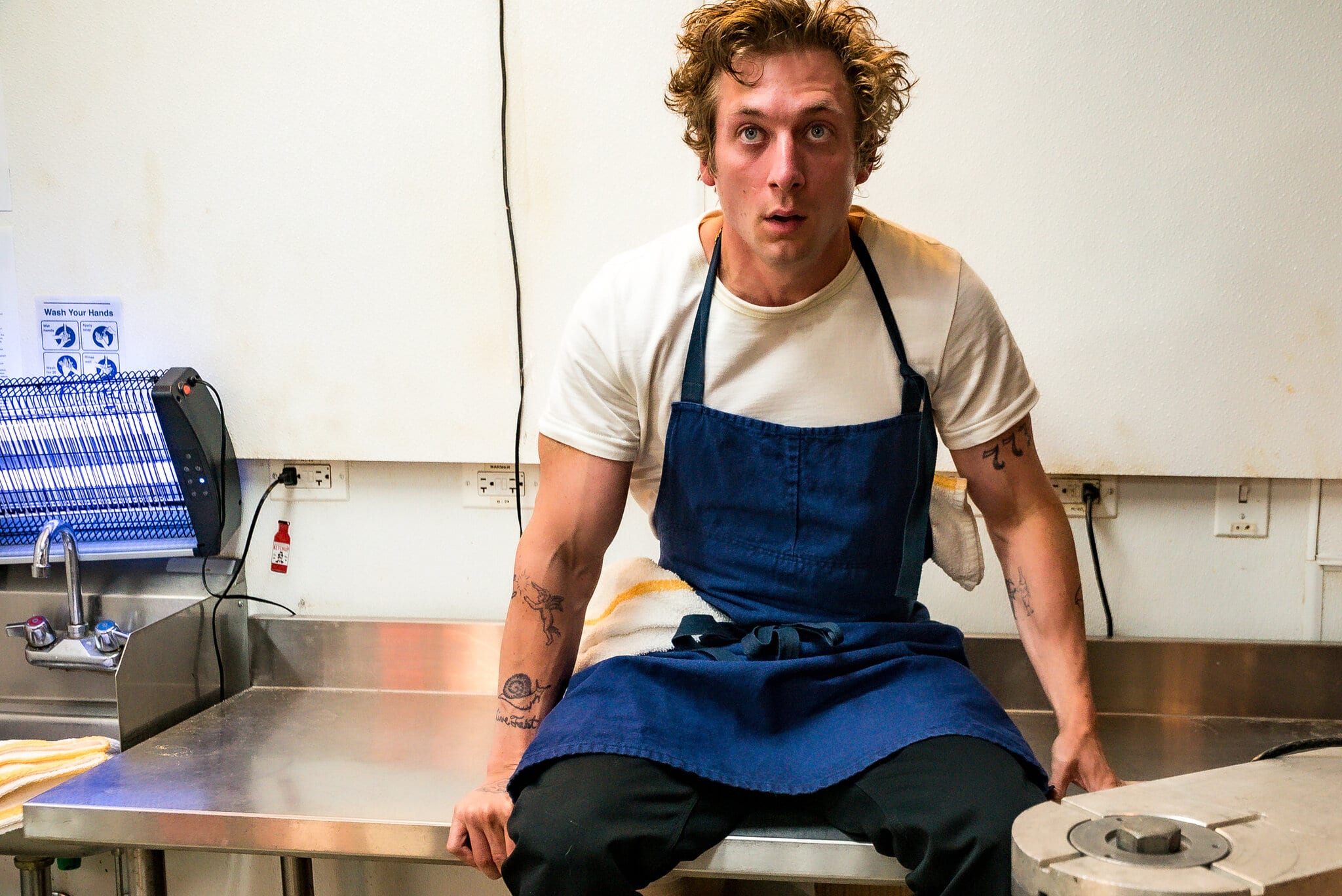 Jeremy Allen White sits on a counter in the kitchen