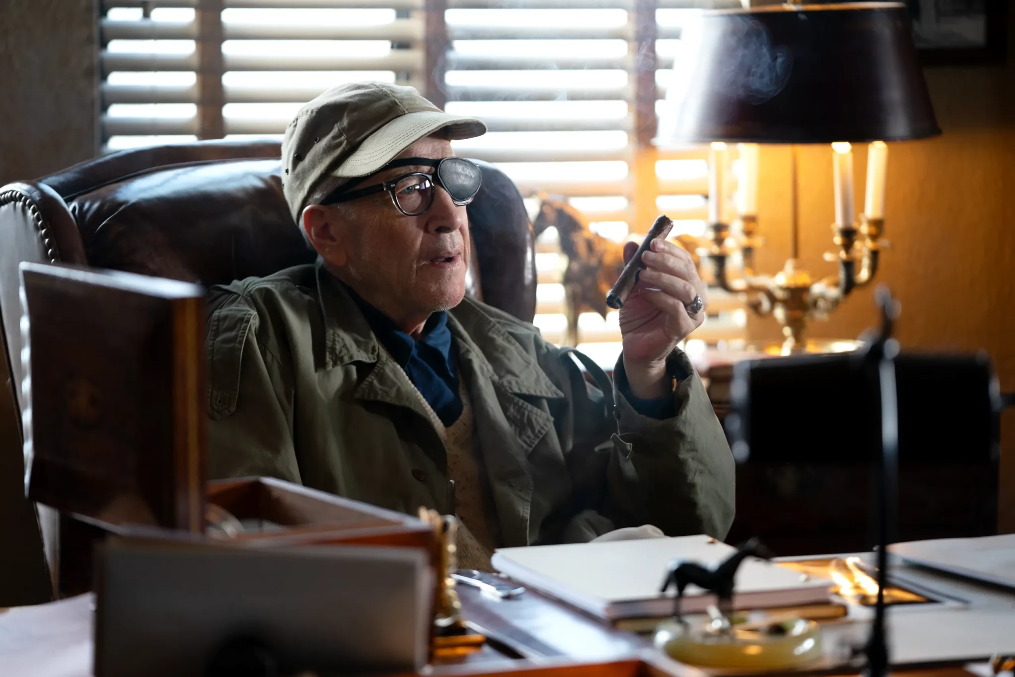 David Lynch as John Ford, sitting behind his desk, cigar in hand