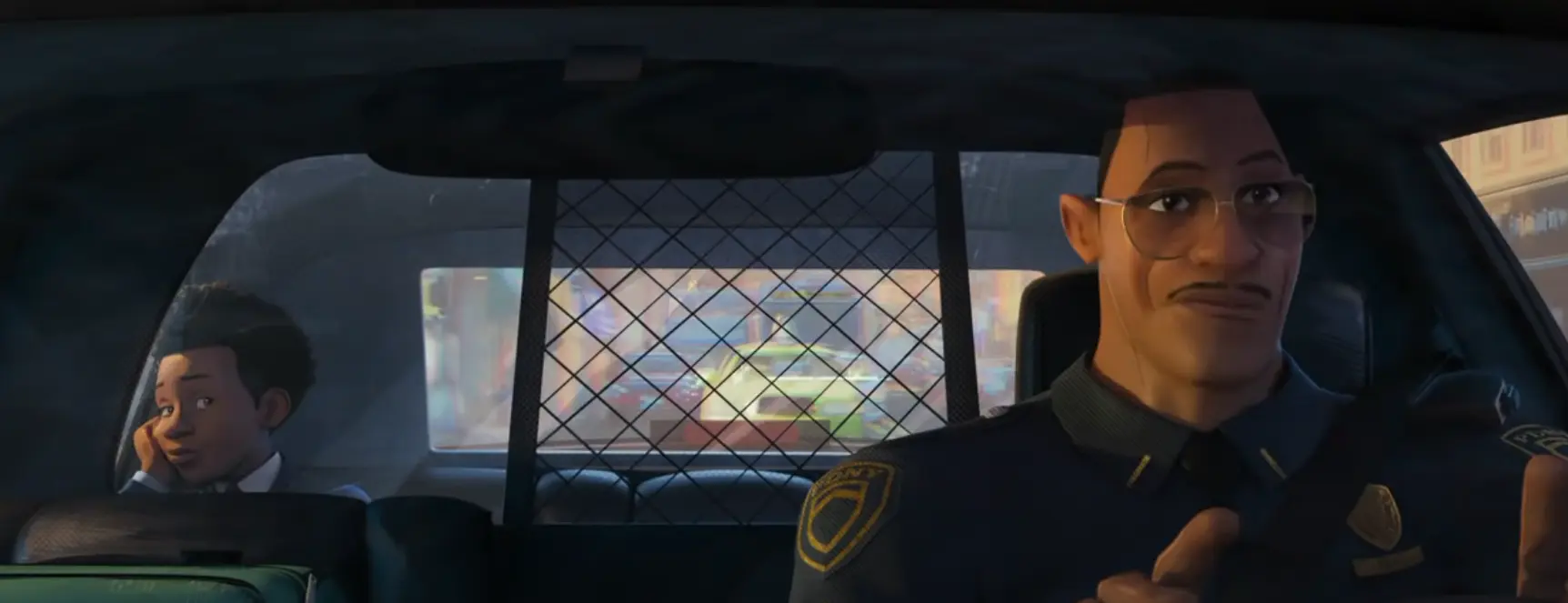 Miles sits in the back seat as his father drives his patrol car