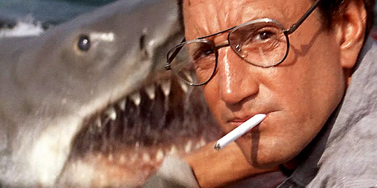 Roy Scheider smoking a cigarette with a huge shark behind him