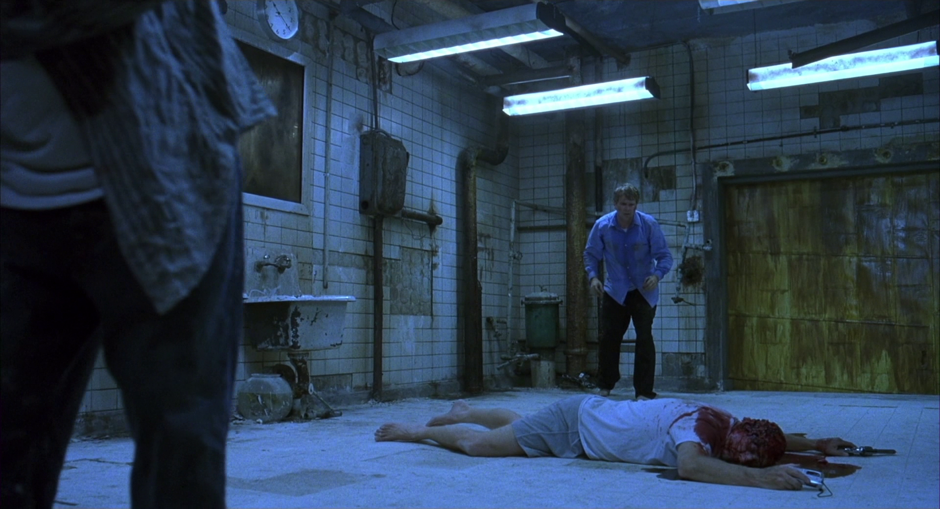 2 men stand over a body on the floor of a bathroom in Saw