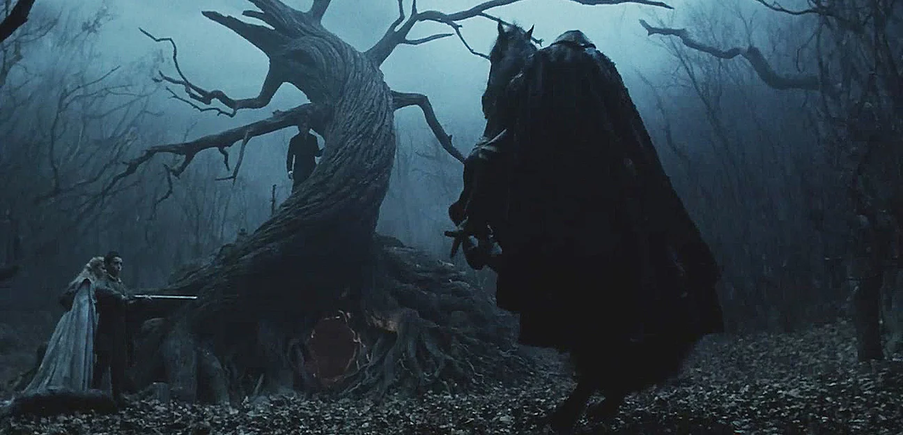 Ichabod, Katrina and young Masbeth near the twisty tree trunk and the towering Horseman