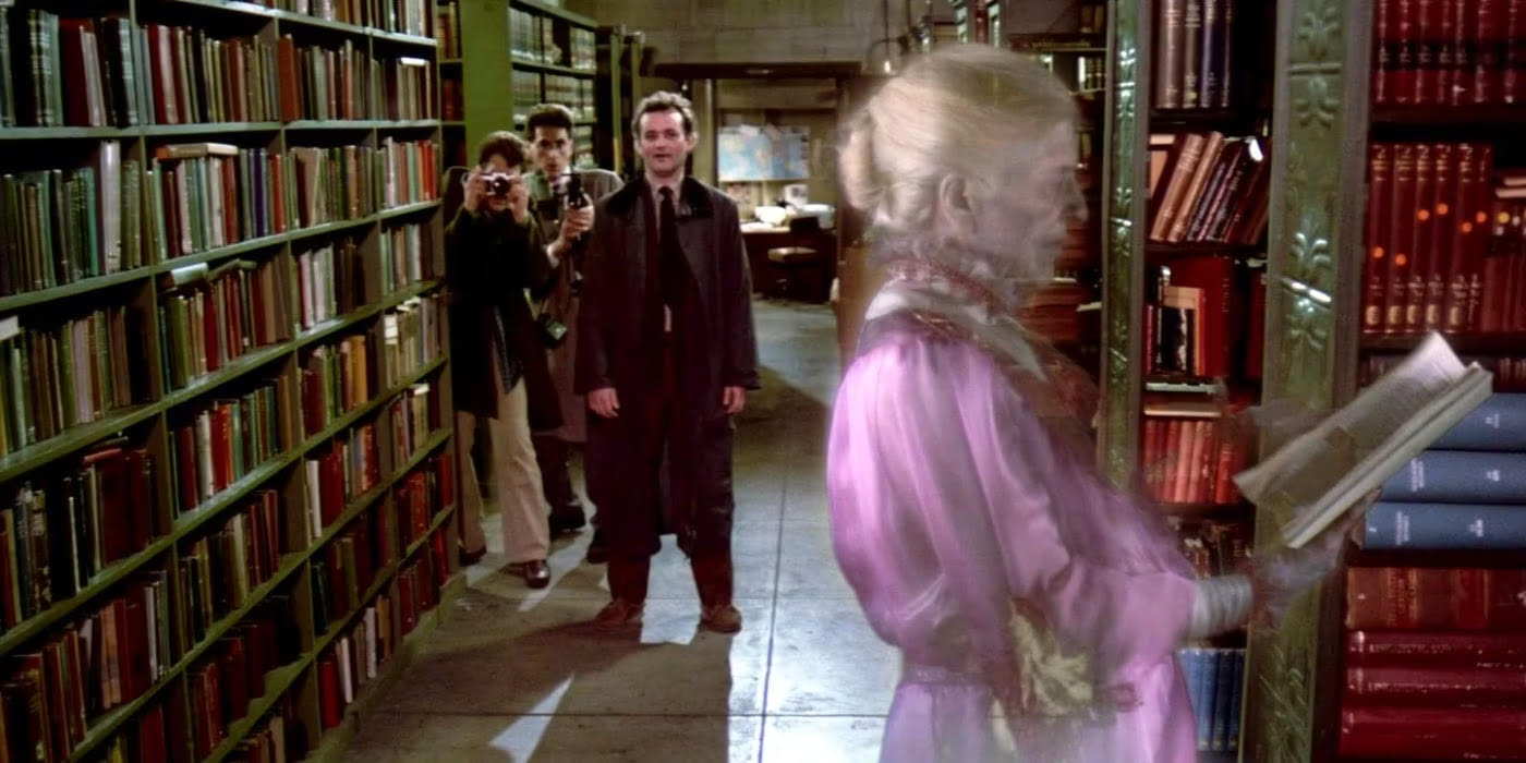 the 4 ghostbusters in a library near stakes of books