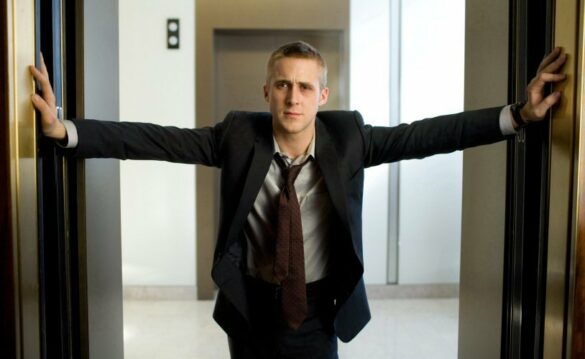 Ryan Gosling in a suit and a necktie, arms extended to his side