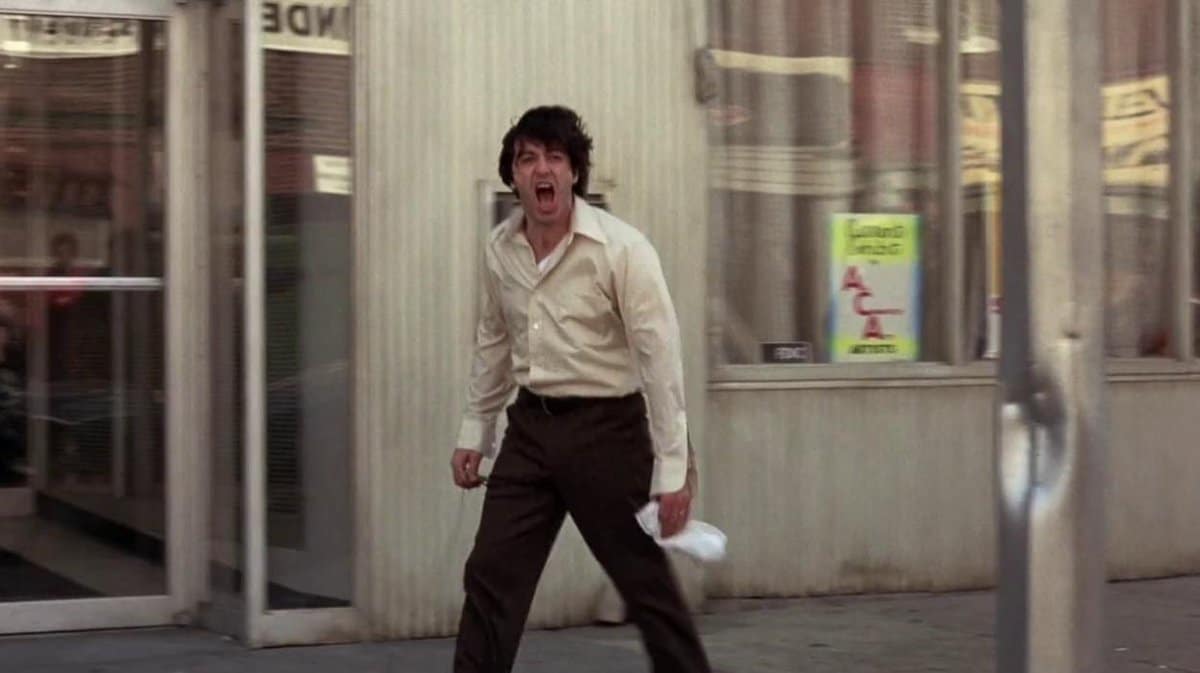 Sonny shouting on the sidewalk outside the bank