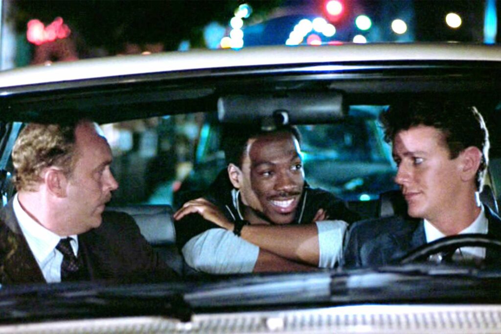 Axel in the back seat of the police car with Taggart and Rosewood in the front
