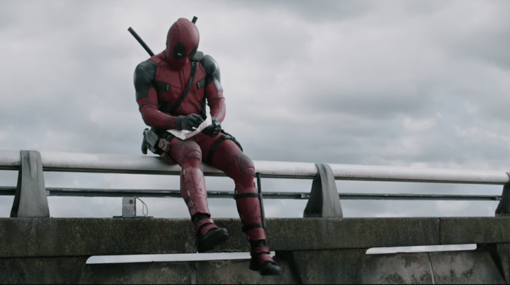 Deadpool sits on the railing on a bridge