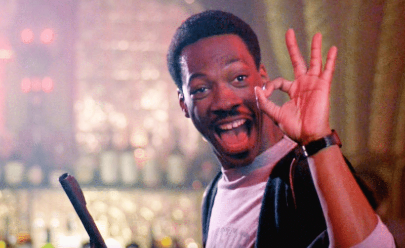 Axel Foley with an I'm OK hand signal