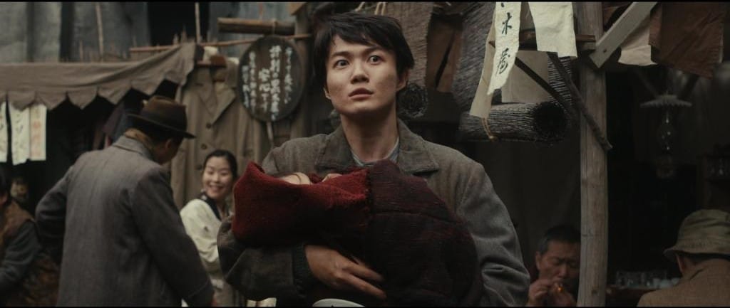 Shikishima holds a baby in a blanket