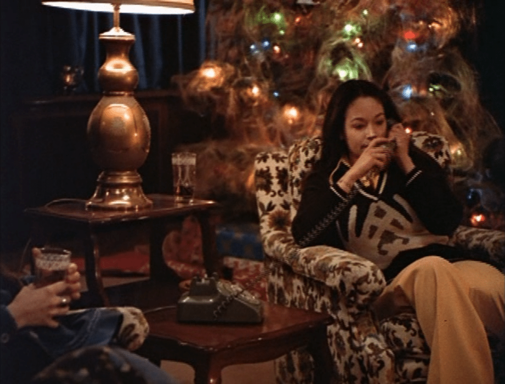 Sorority girl Jess sitting in a chair near a Christmas tree with ornaments