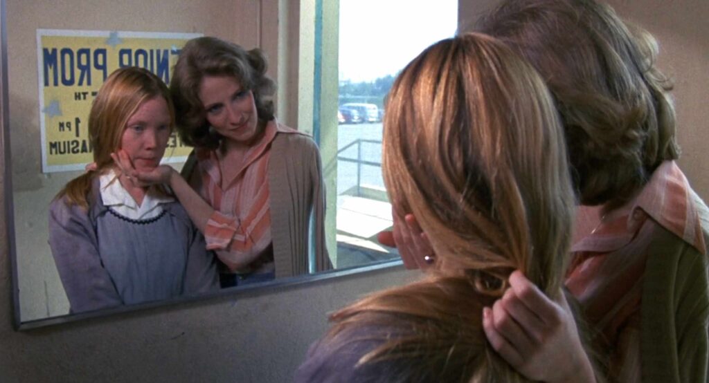 Mrs. Collins and Carrie looking into a mirror