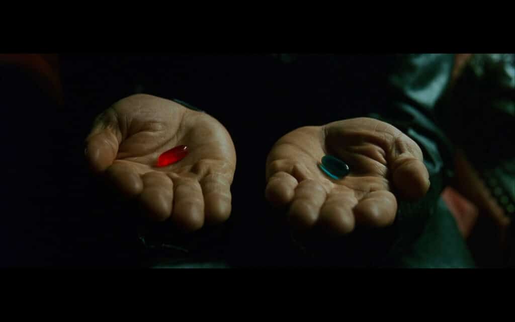 2 open hands - one holding a green pill, the other holding a red pill