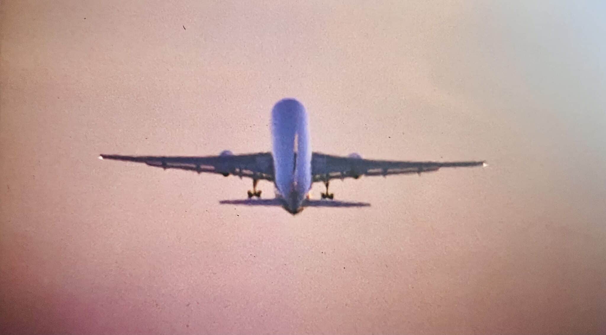 An airplane flies against the clear sky