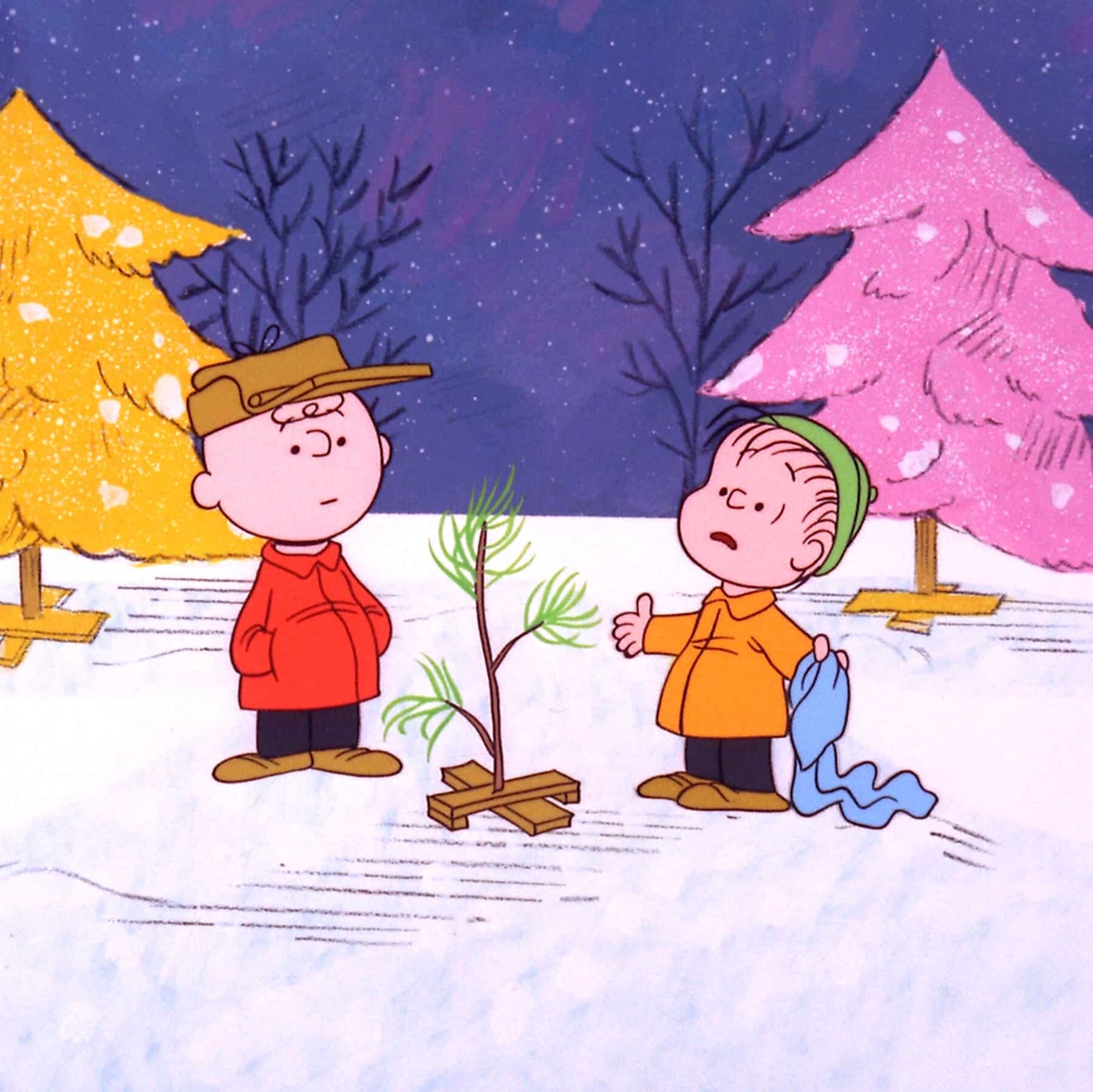 Charlie Brown and Linus outside on the snow-covered ground with their small Christmas tree.