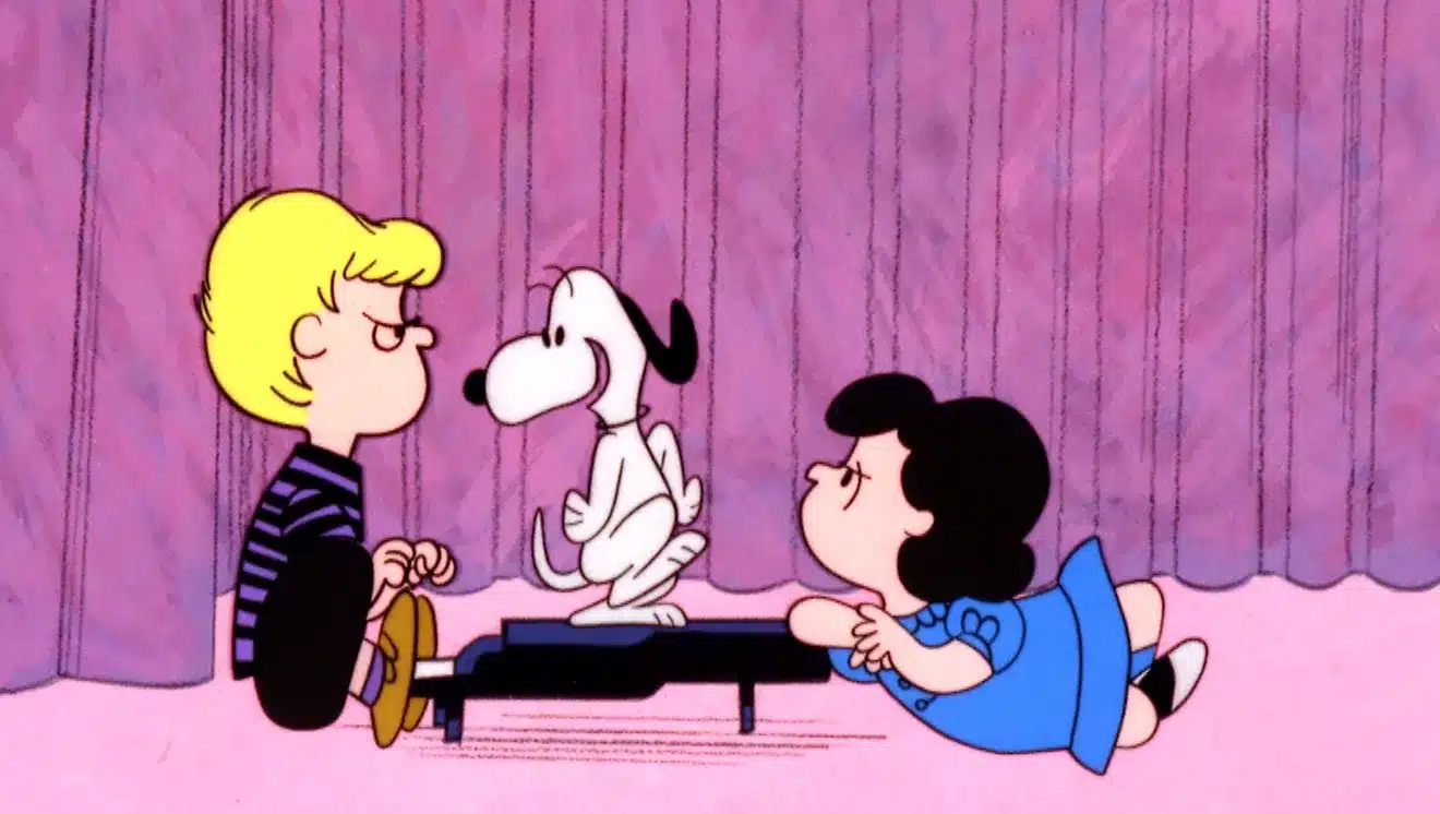 Schroeder and Lucy sit at the piano while Snoopy dances on the piano top