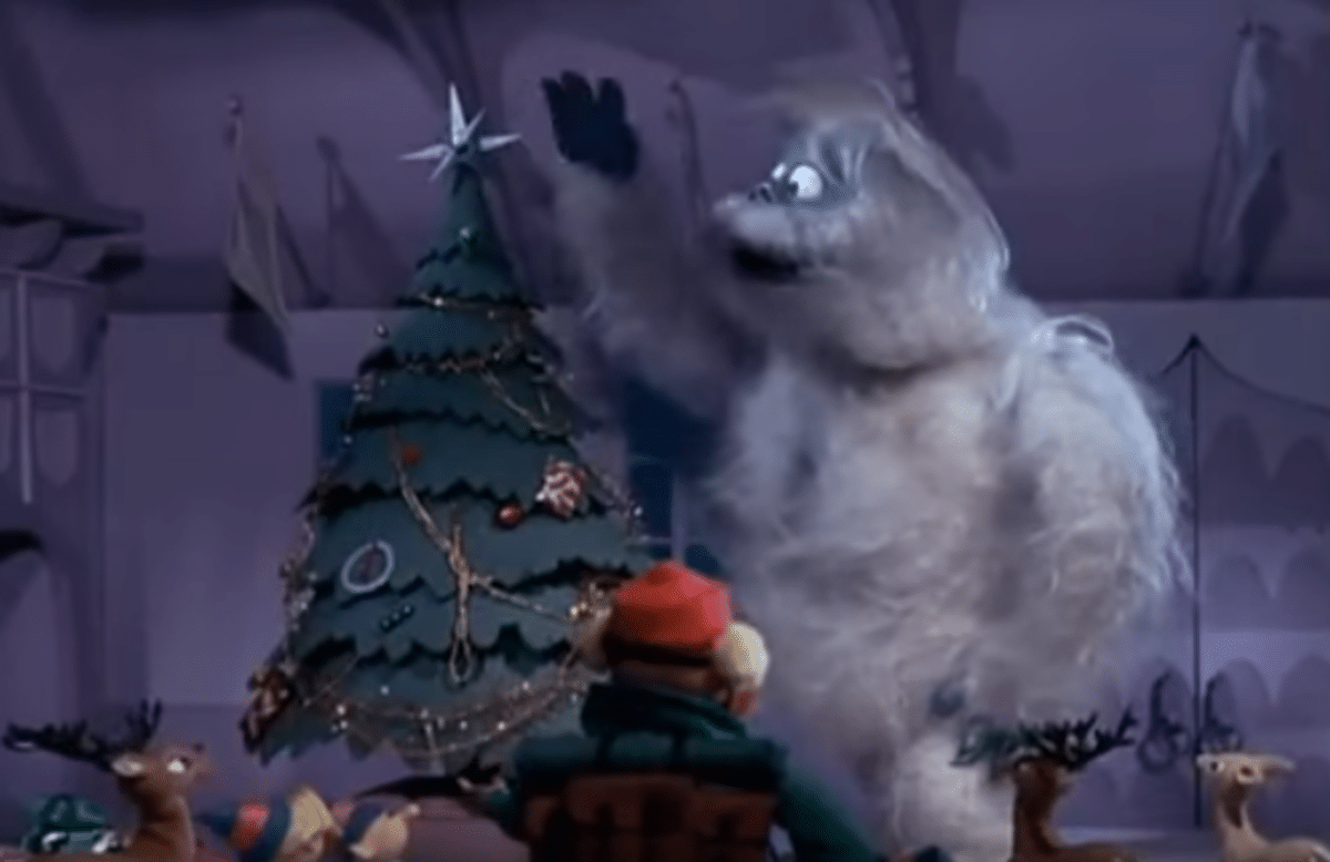 The toothless Bumble stands next to a Christmas tree