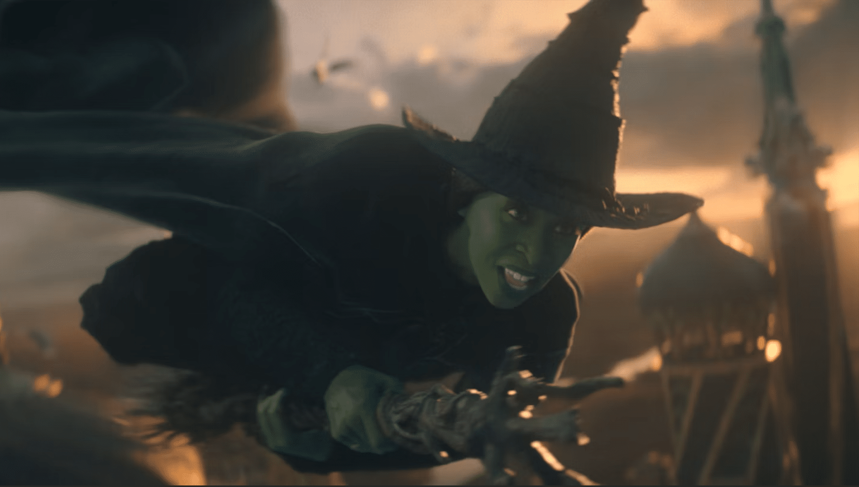 Elphaba wearing her black hat and riding her broom through the skies
