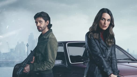 Ben Whishaw and Keira Knightley holding guns as they stand in front of a car