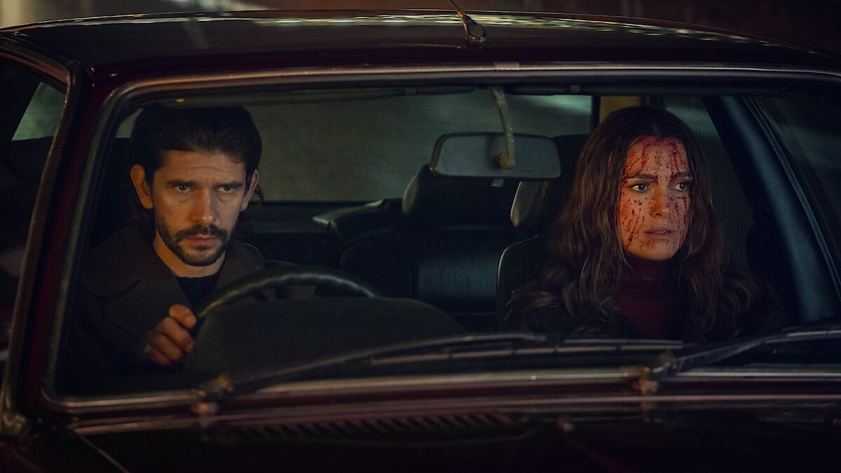 Ben Whishaw and Keira Knightley in the front seat of a car with blood splattered on Keira's face