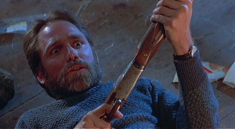 Stathis on his back on the floor, holding a shotgun