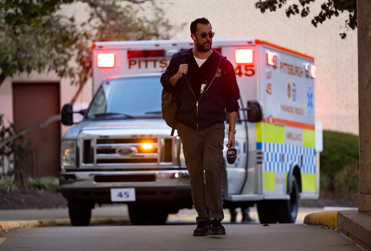 Noah Wylie walking on the street with an ambulance behind him