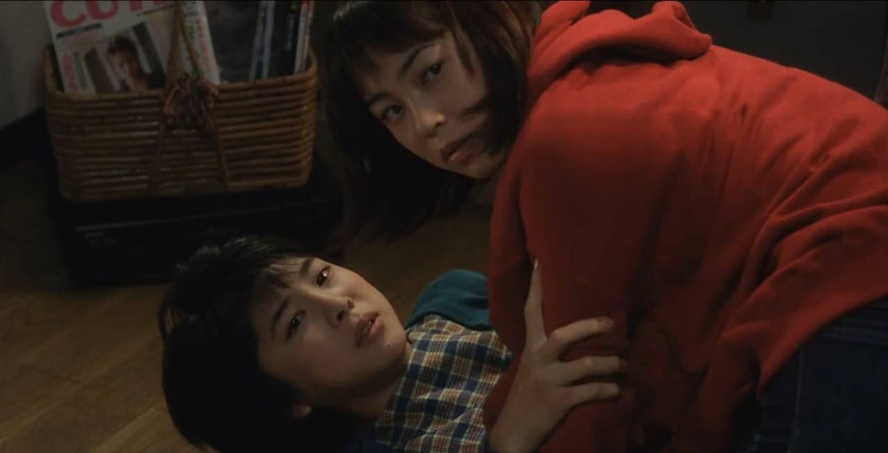 Reiko on the floor with Tomoko on top of him.