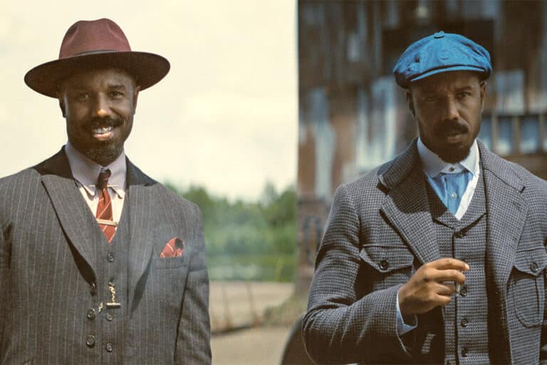 Twin brothers Smoke and Stack stand in front of a barnlike structure in the film Sinners