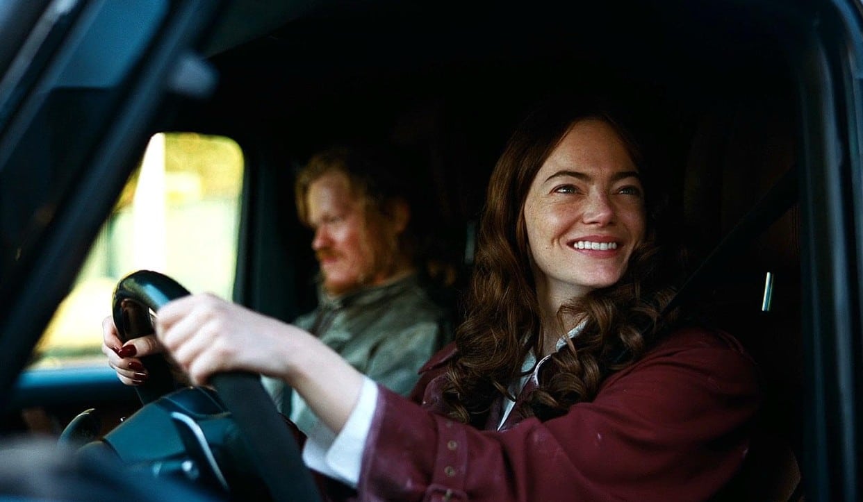 Michelle, wearing a wig, and Teddy sit in the front seat of her car
