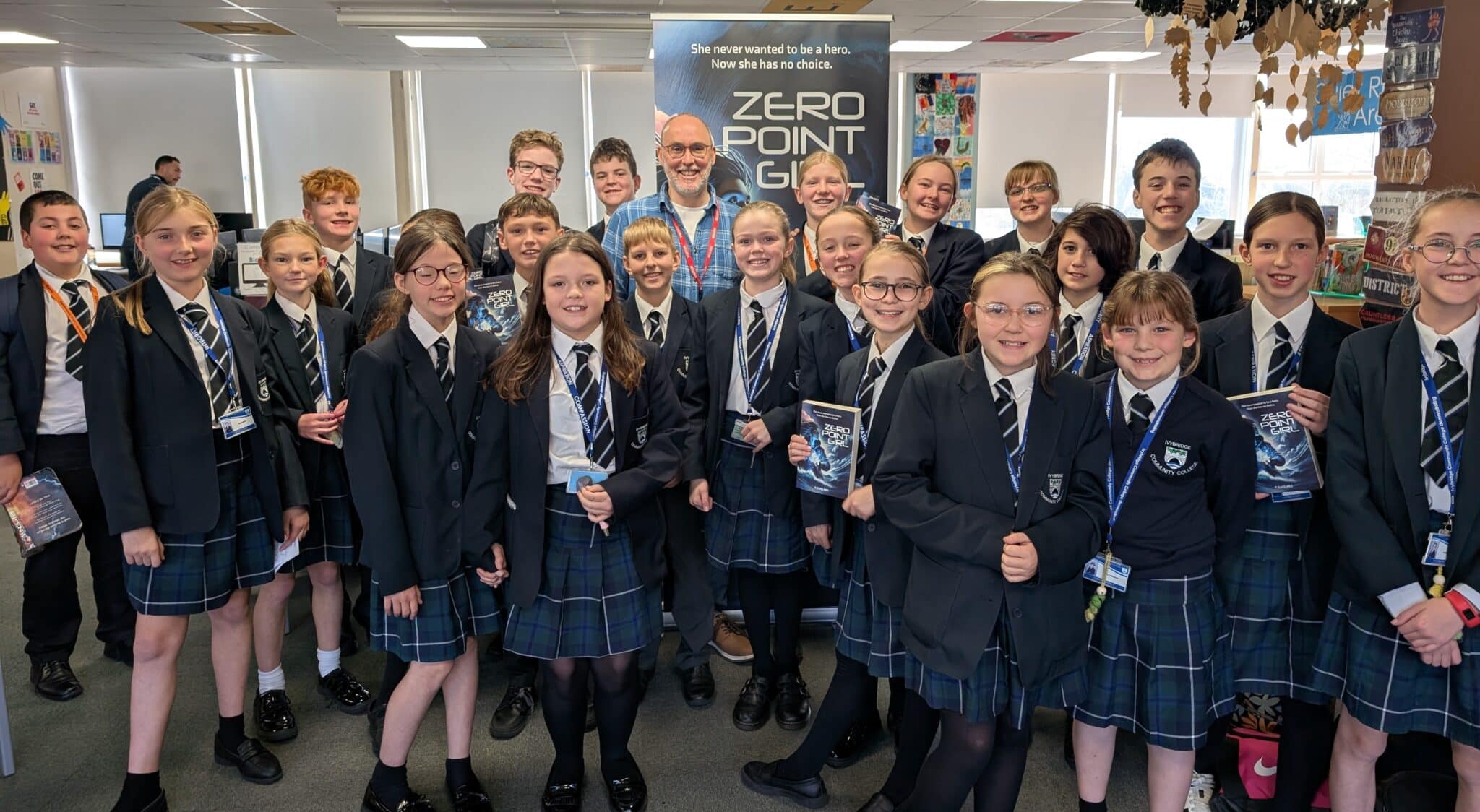 Author Rob Holmes surrounded by a middle school class of students holding his Zero Point Girl novel