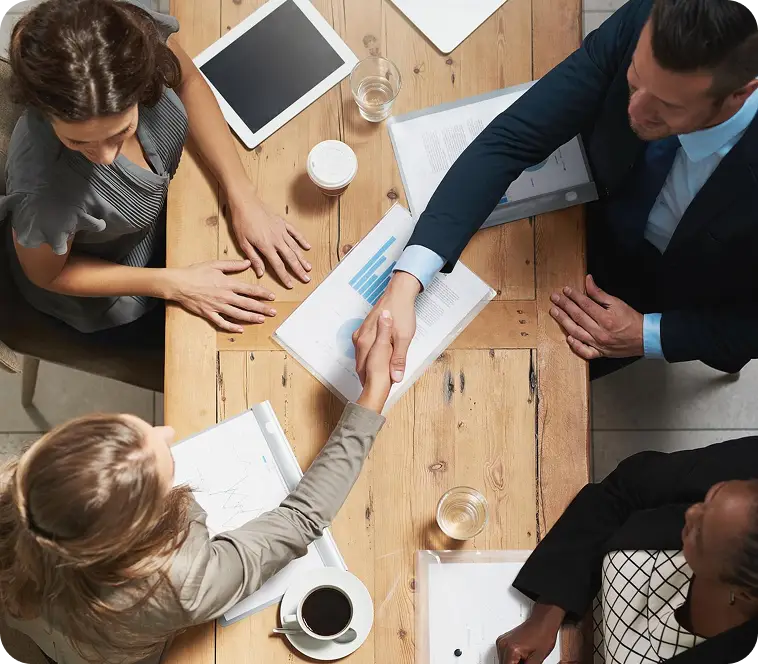 Man and woman shaking hands over a table with papers