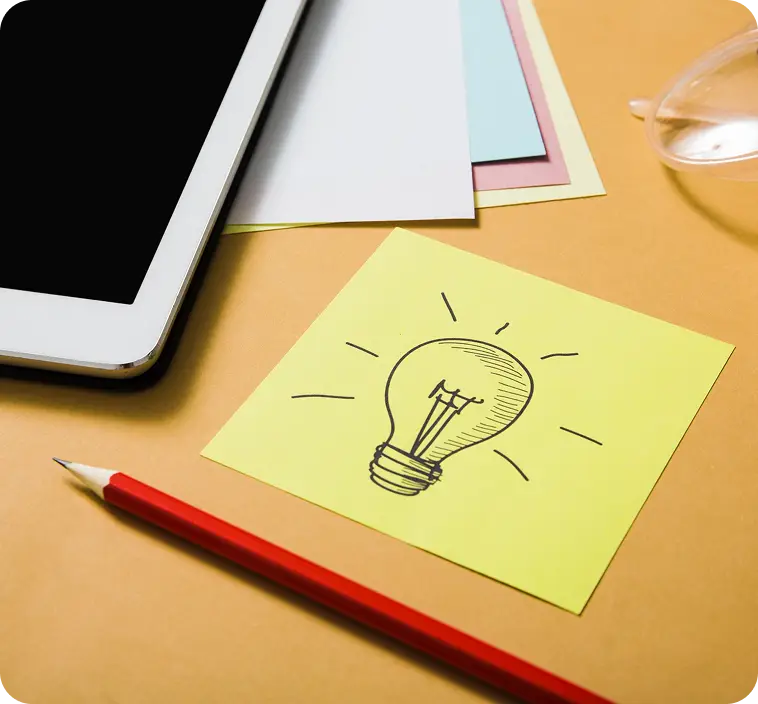 On the table lies a tablet, a pencil and a sheet of paper with a drawn light bulb