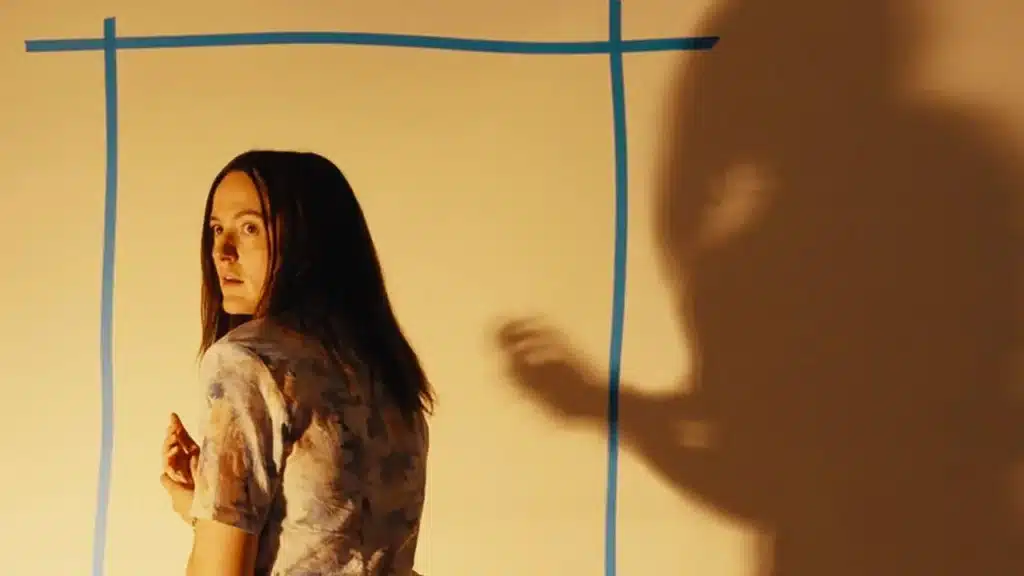 Mary in a backoom with the shadow of a large creature behind her.