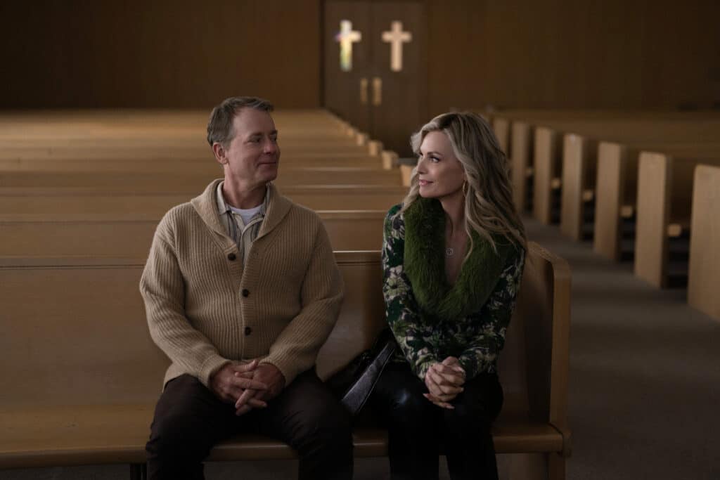 Greg Kinnear sits in a pew next to Michelle Pfeiffer