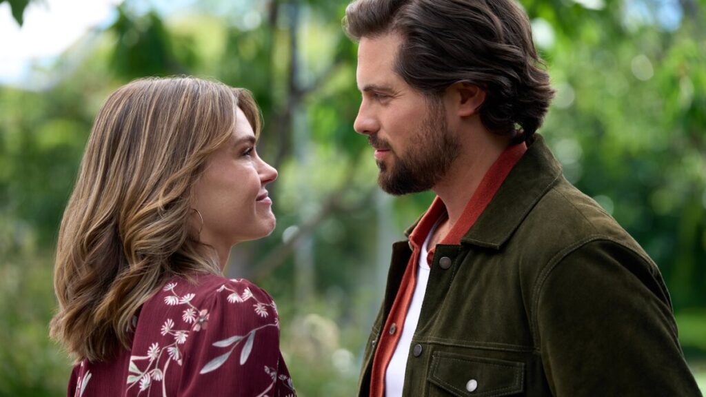 Aimeé Teegarden and Chris McNally staring at each other in a forest
