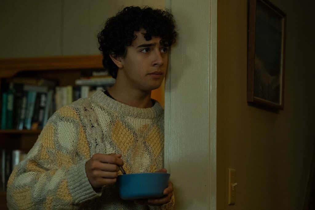 Evan stands in the kitchen eating cereal out of a bowl