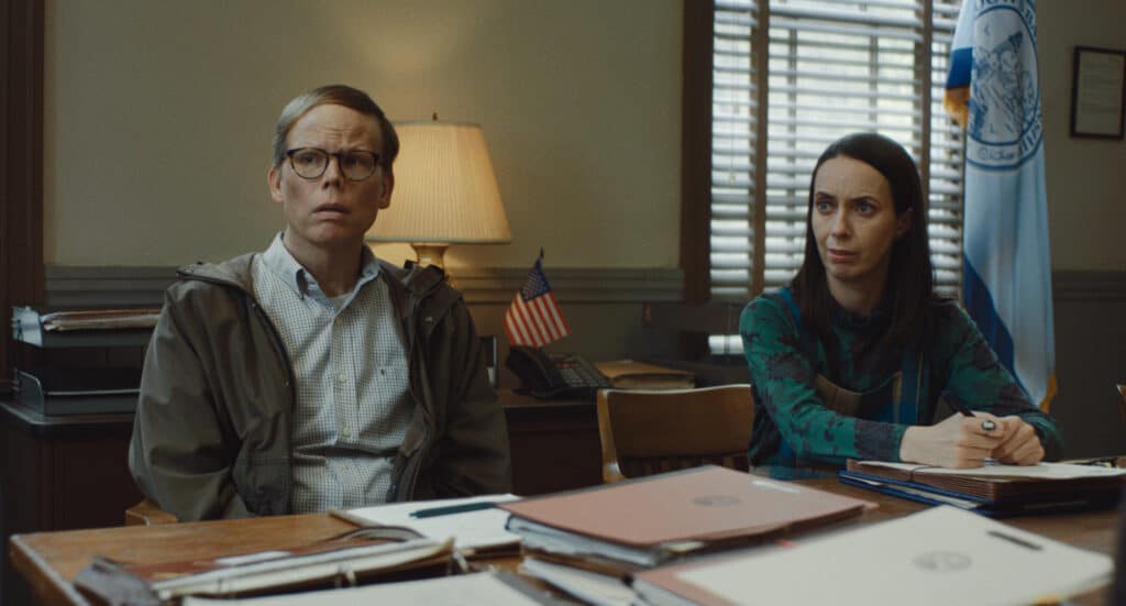 Dale and Patricia sit at a table littered with files